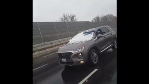 Toglie la neve dal parabrezza mentre viaggia in autostrada