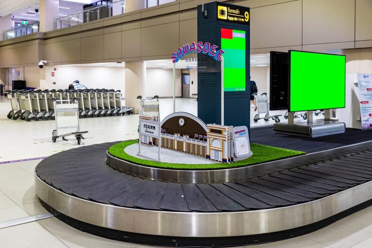 Area ritiro bagagli aeroporto con nastro trasportatore circolare e modellino architettonico centrale