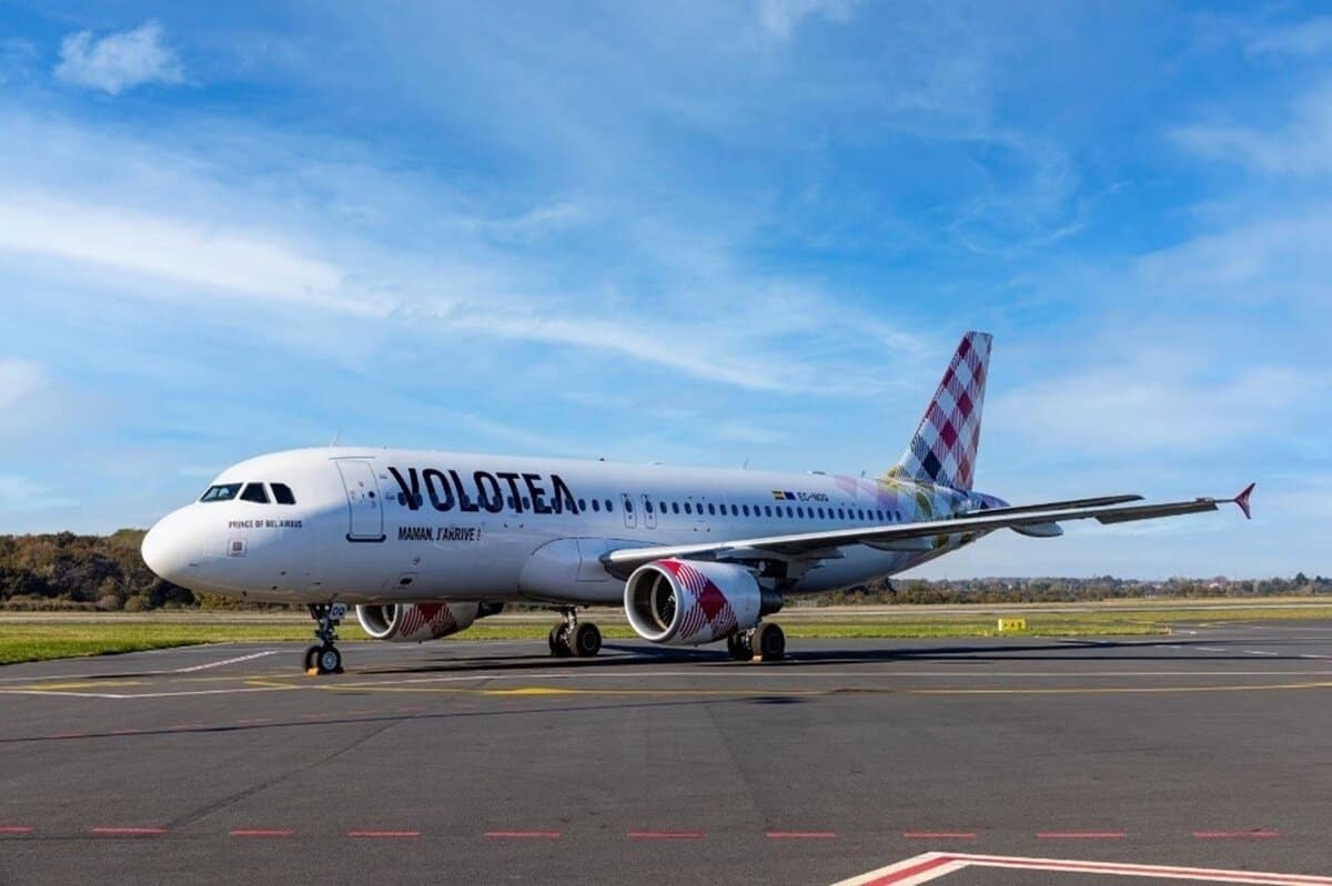 Volotea Airbus A320 bianco con dettagli colorati, parcheggiato su una pista di decollo in un cielo sereno.