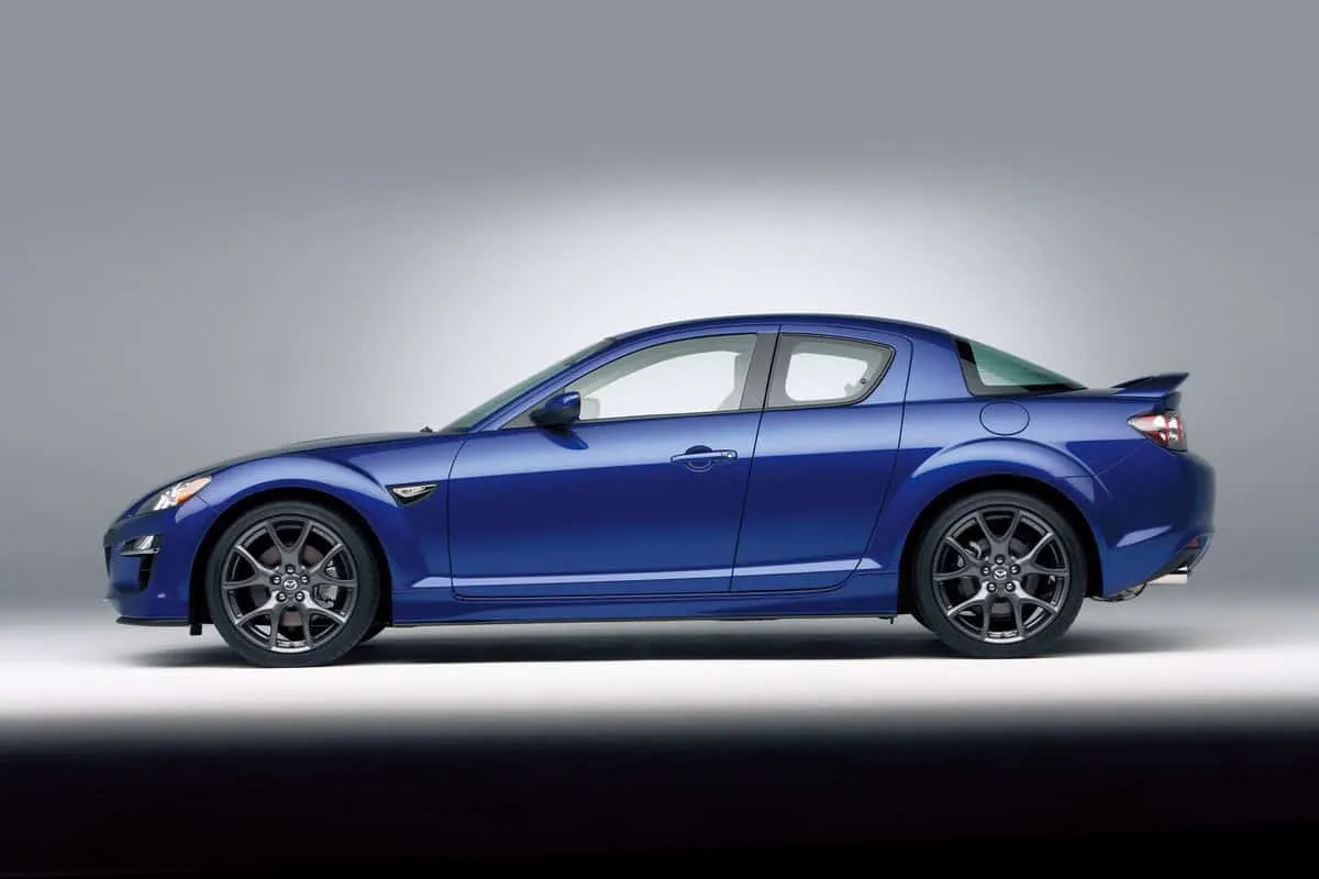 Mazda RX-8 blu vista laterale in studio, auto sportiva compatta, profilo destro, cerchi in lega grigi.